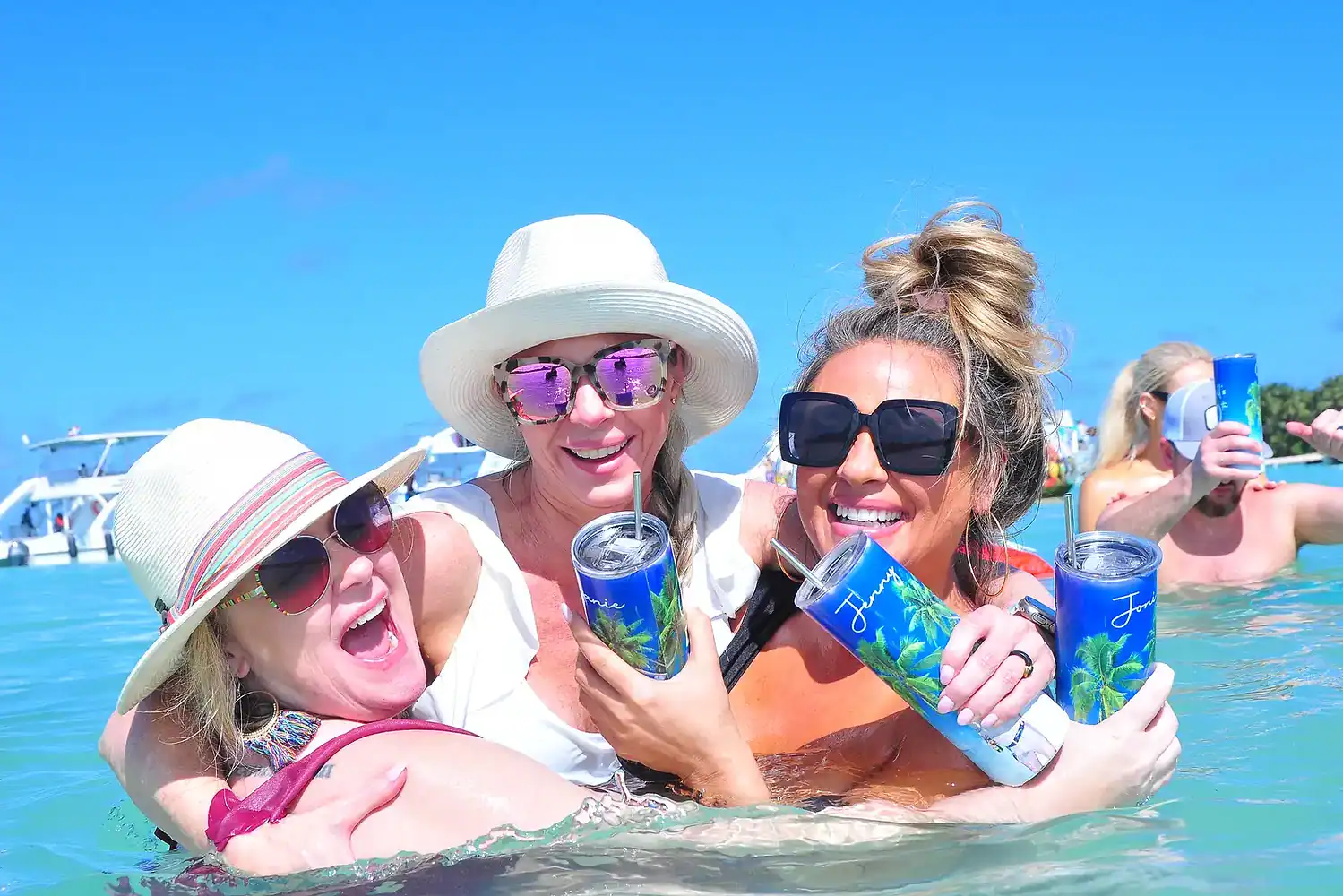 Punta Cana Women in sunglasses and hats having fun with drinks in the Caribbean sea.