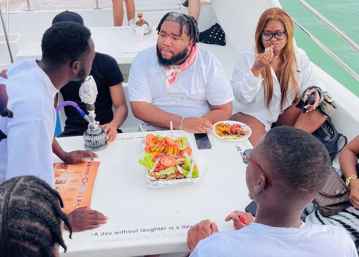 Punta Cana Group of friends dining together on a boat with food and drinks, enjoying a sunny day in Punta Cana.