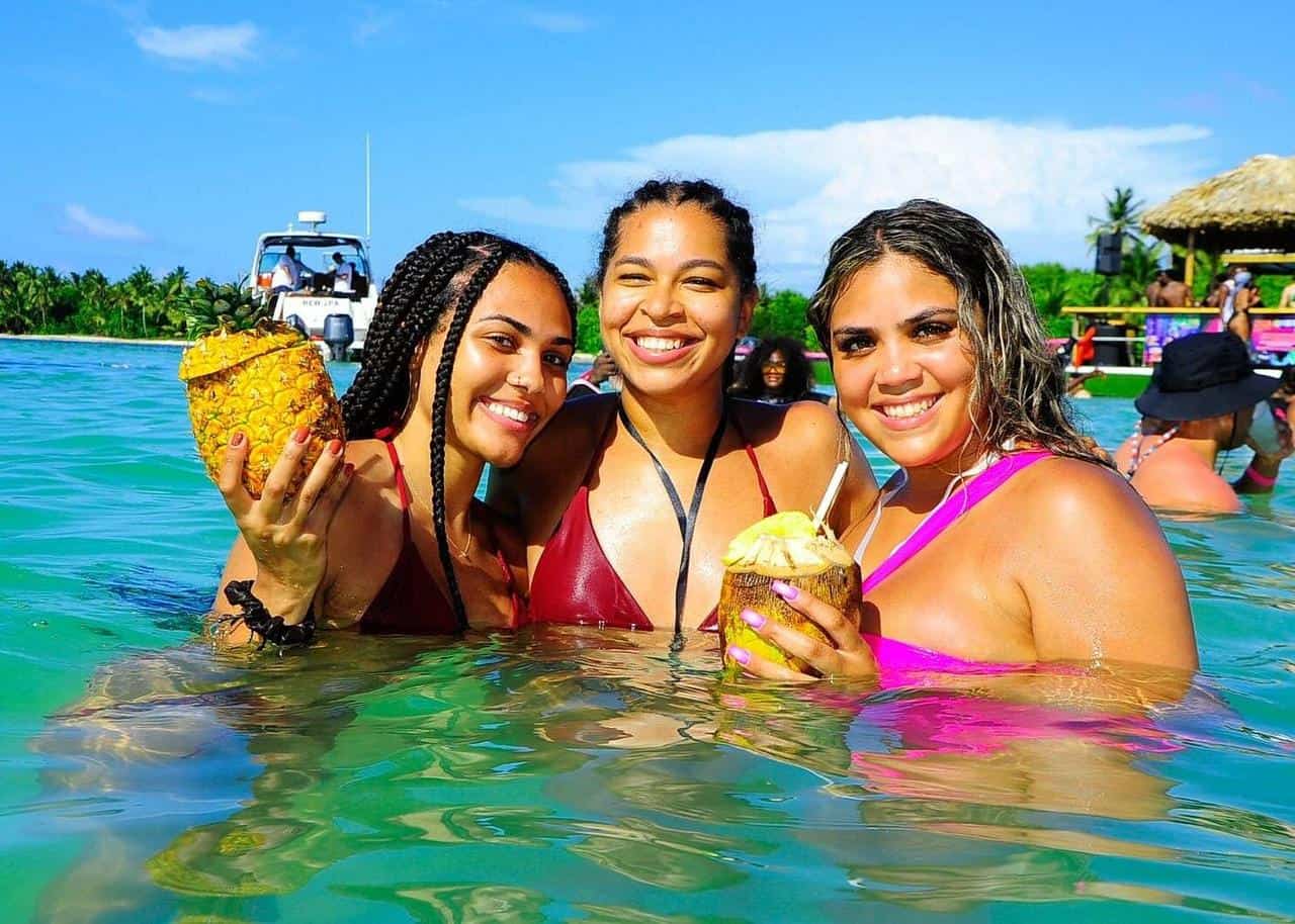 Punta Cana Three women enjoying a tropical beach party with pineapples in Punta Cana waters.