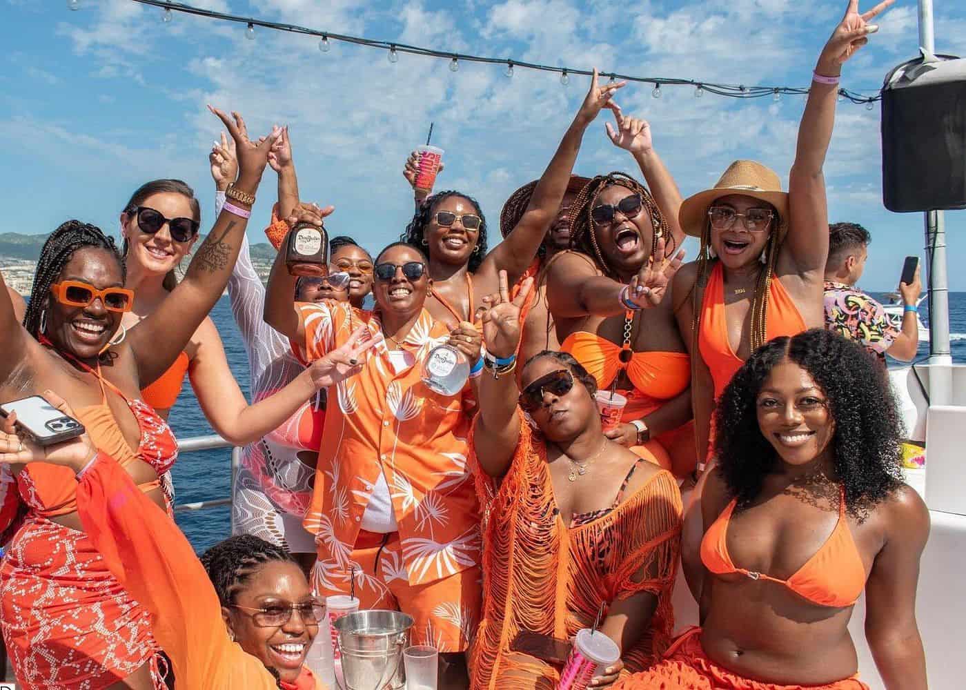 Punta Cana Women enjoying a lively party boat cruise in Punta Cana, Dominican Republic, wearing orange outfits.