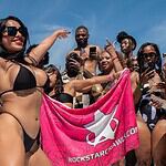 Punta Cana Women enjoying a lively beach party holding a pink Rockstar Crawls flag.