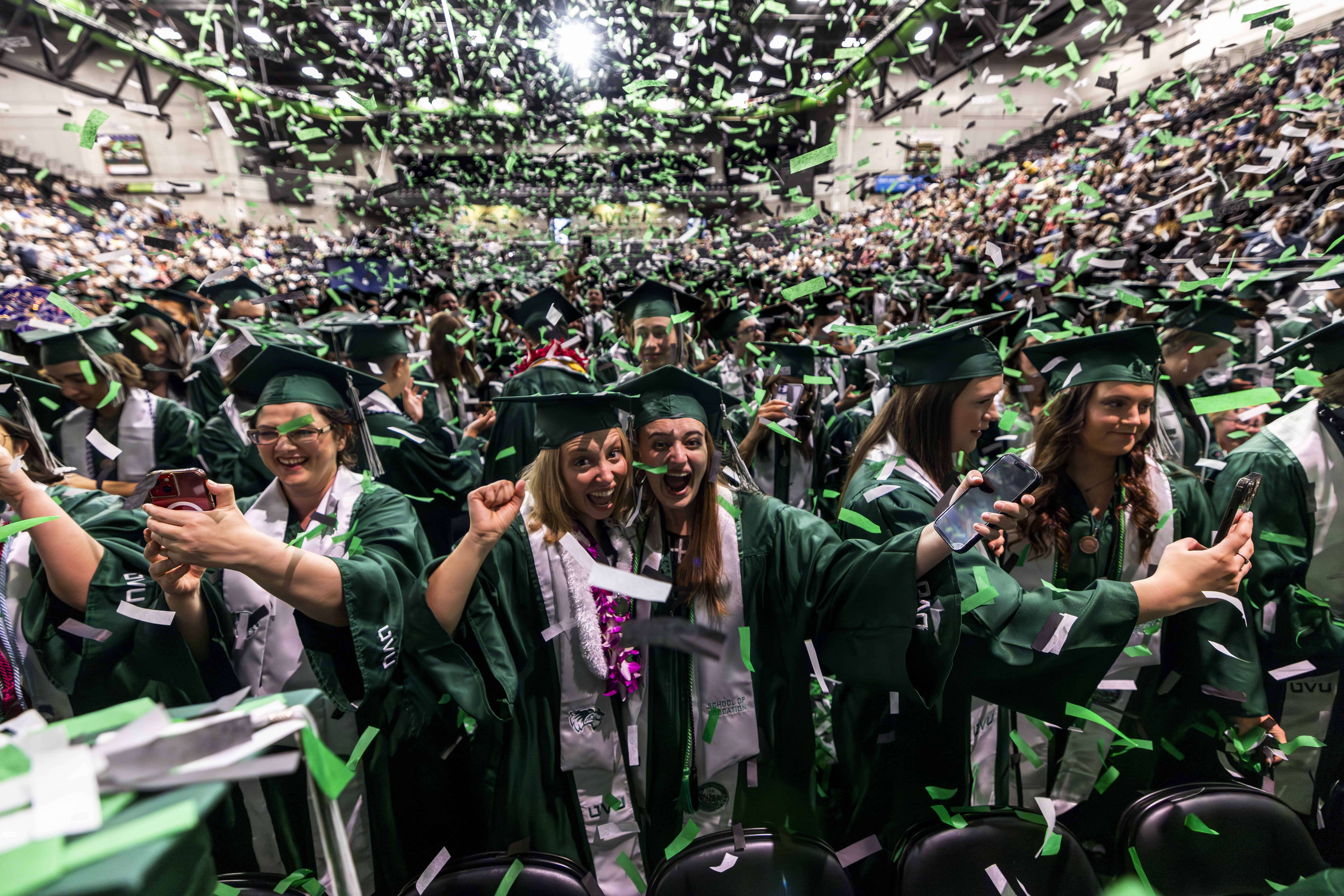 Graduates celebrating at a UVU graduation ceremony with confetti and joyful expressions.
