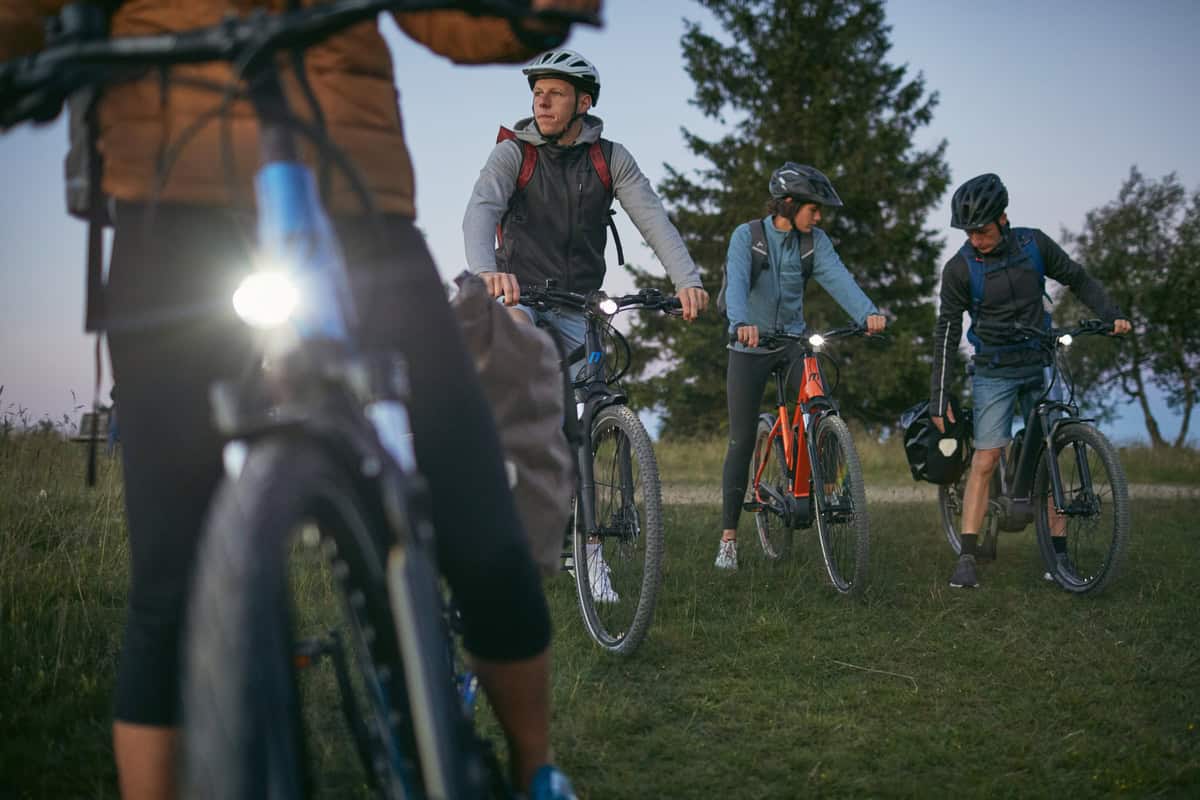 Velociped Fahrradgruppe im Park Fahrradfahrer im Park bei Sonnenuntergang, Gruppe mit Helm und Rucksack.