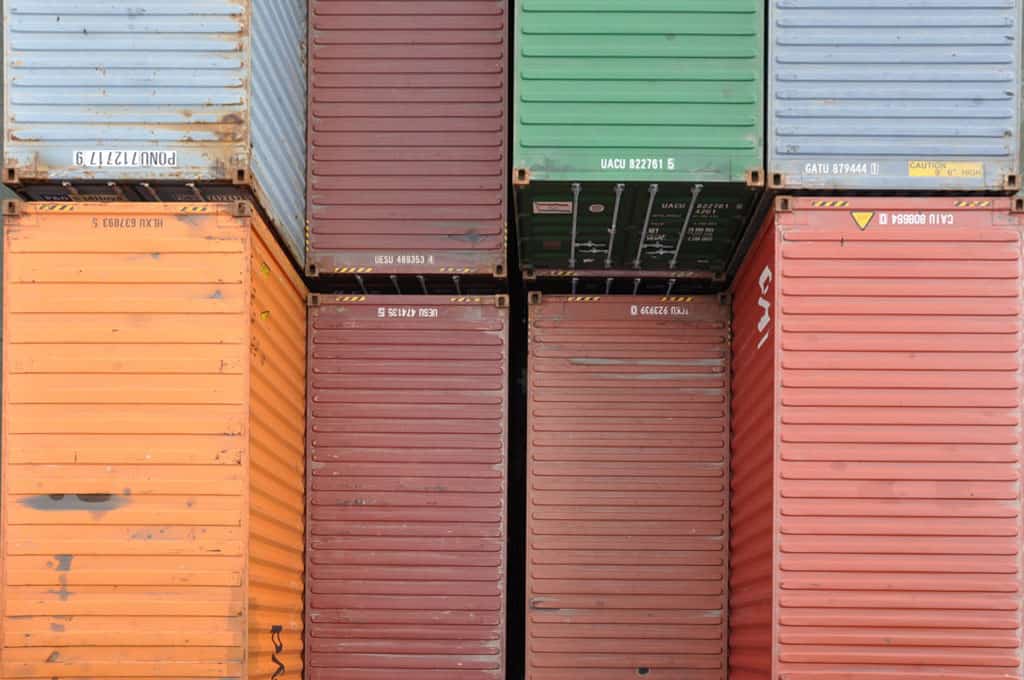 Frachtcontainer in verschiedenen Farben, industriell gelagert und sortiert.