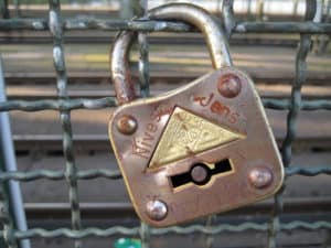 Verschlossung an Zaun, Sicherheitsverschluss, rostfreier Schließmechanismus, Fokus auf Sicherheitstechnik.