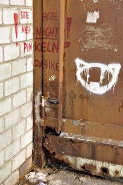 Verrostete Metalttür mit Graffiti und Schreiben, urbane Kunst, Rost, Abnutzung, Graffiti-Kunst, beschädigtes Gebäude.