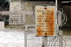 Eingezäunter Sicherheitsbereich mit Stacheldraht und Verbotsschild, Umwelt- und Sicherheitszone.