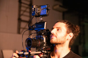 Fotógrafo com câmera profissional captando vídeo em estúdio.