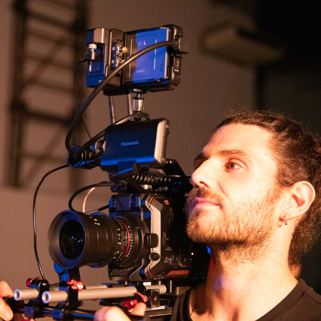 Cineasta com câmera profissional em estúdio de filmagem, foco na produção audiovisual.