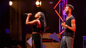 Estudantes a cantar ao microfone durante evento na World Academy, centro de formação e desenvolvimento.