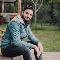 Homem sorridente ao ar livre, promovendo educação e crescimento pessoal.