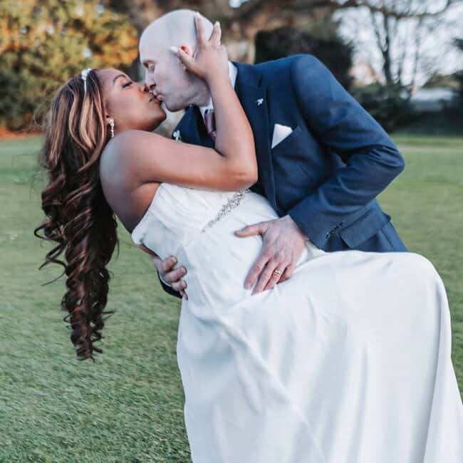 Wensum Valley wedding photographer capturing groom kissing bride on cheek during outdoor portrait