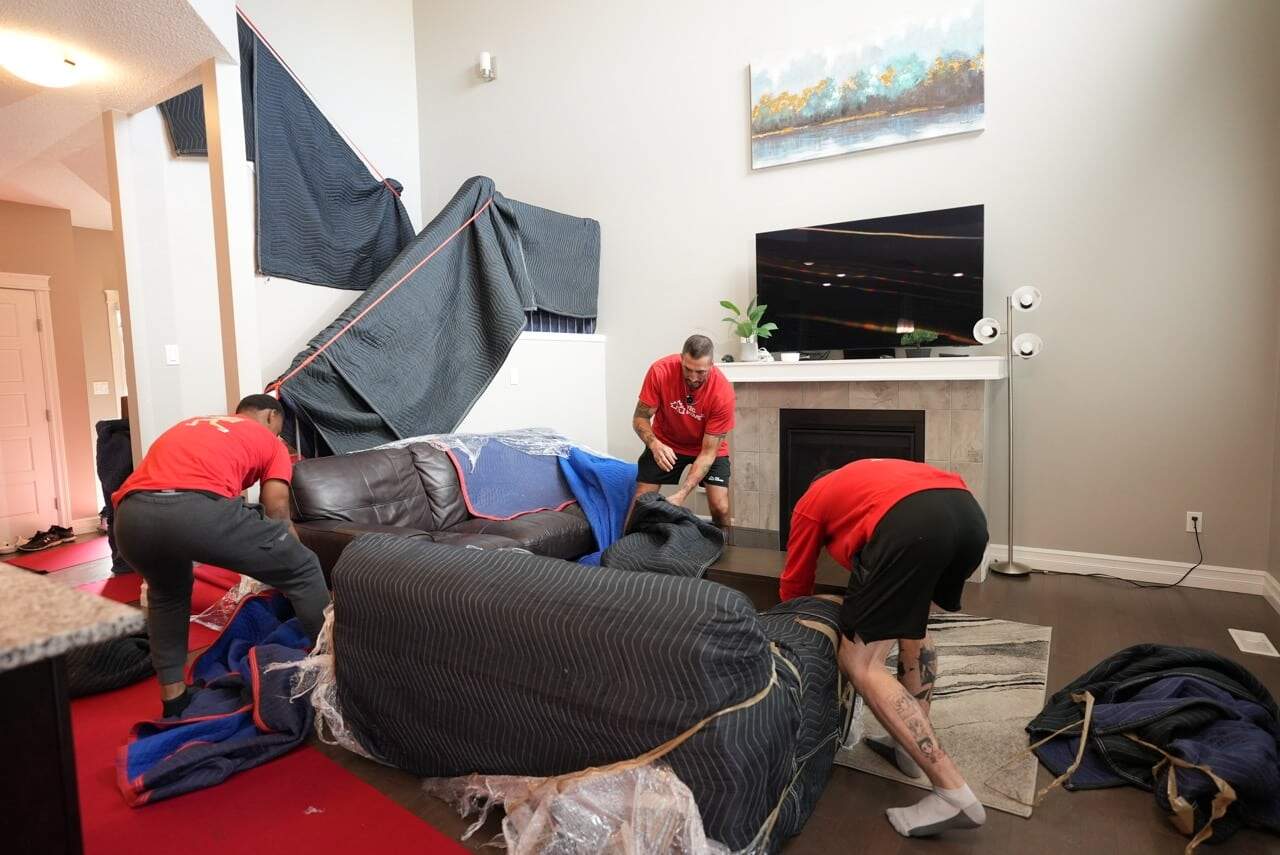 Professional movers handling furniture and packing in a residential setting.