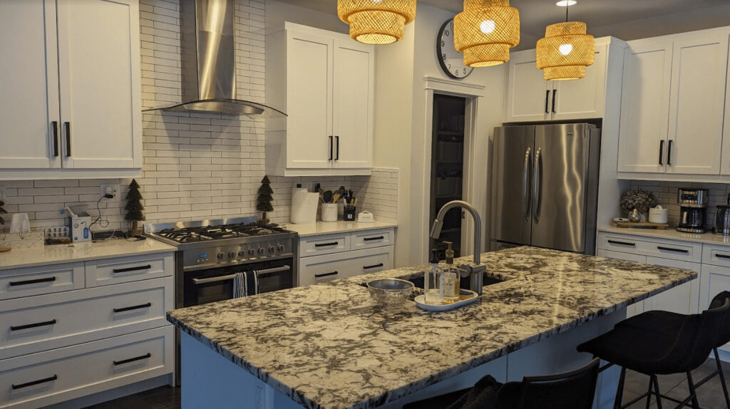 Modern kitchen with white cabinets, stainless steel appliances, pendant lights, and a large marble island.