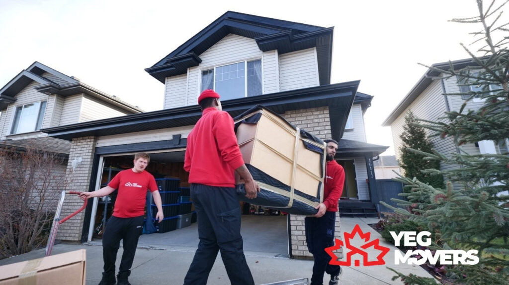 Movers in Edmonton carrying a large sofa into a house.