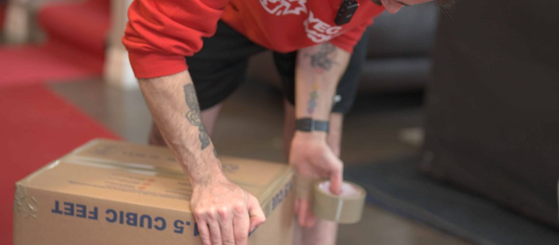 Man packing a cardboard box with vinyl records for moving and protection.