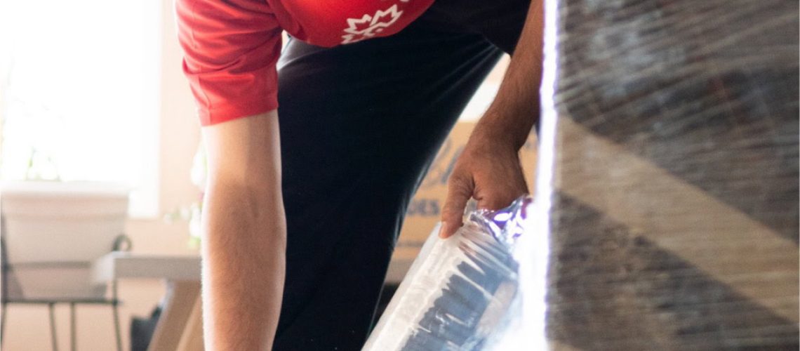 Professional mover wrapping furniture for safe transport in Edmonton.