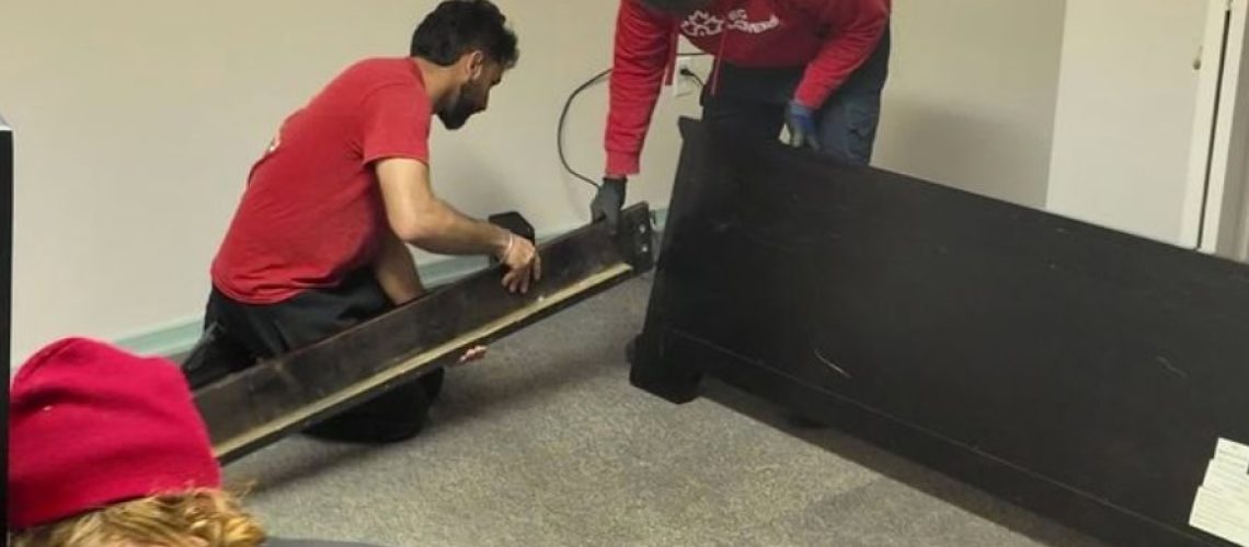 Movers assembling furniture in a room for a school-year move.