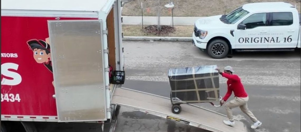 Moving truck unloading furniture in front of a modern house in Edmonton.