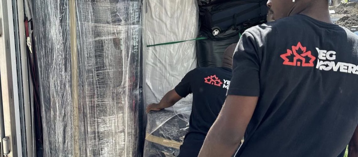 YEG Movers crew loading plastic-wrapped furniture and mattresses into a moving truck during a residential move.