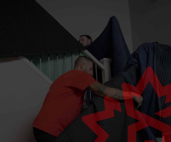 Movers carrying a large sofa up the stairs in Edmonton home.