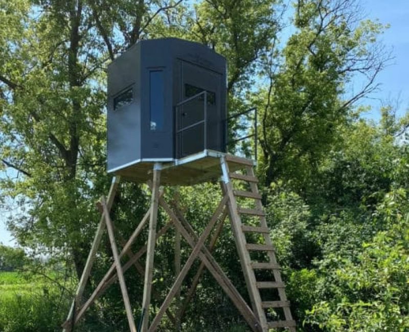 tall deer stand next to trees in the woods