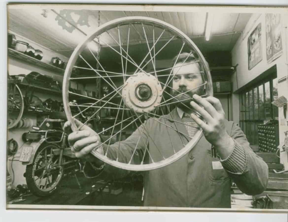 Historischer Fahrradreifen im Werk Mann hält alten Fahrradreifen in Werkstatt, Vintage-Atmosphäre.