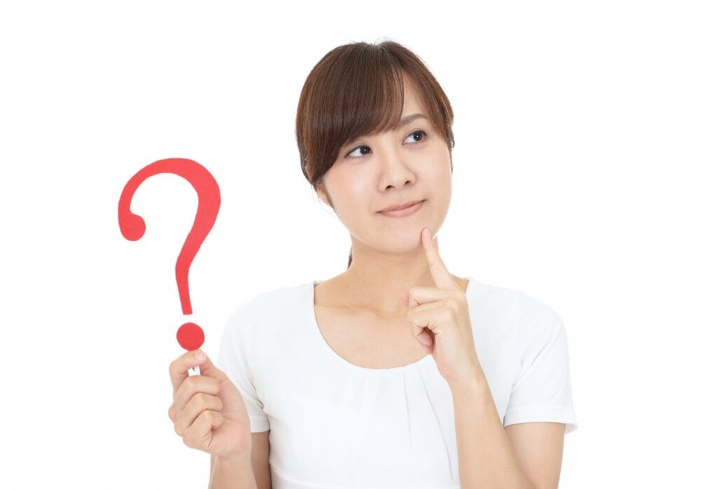 赤いクエスチョンマークを持って考え込む女性の写真