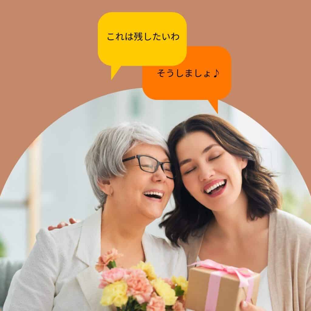 高齢の母親と娘が笑顔で話し合い、花とプレゼントを手にしている様子