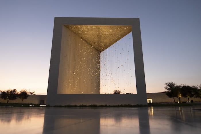 A stunning shot of The Founder's Memorial illuminated by lights as the sun sets in the background. copy