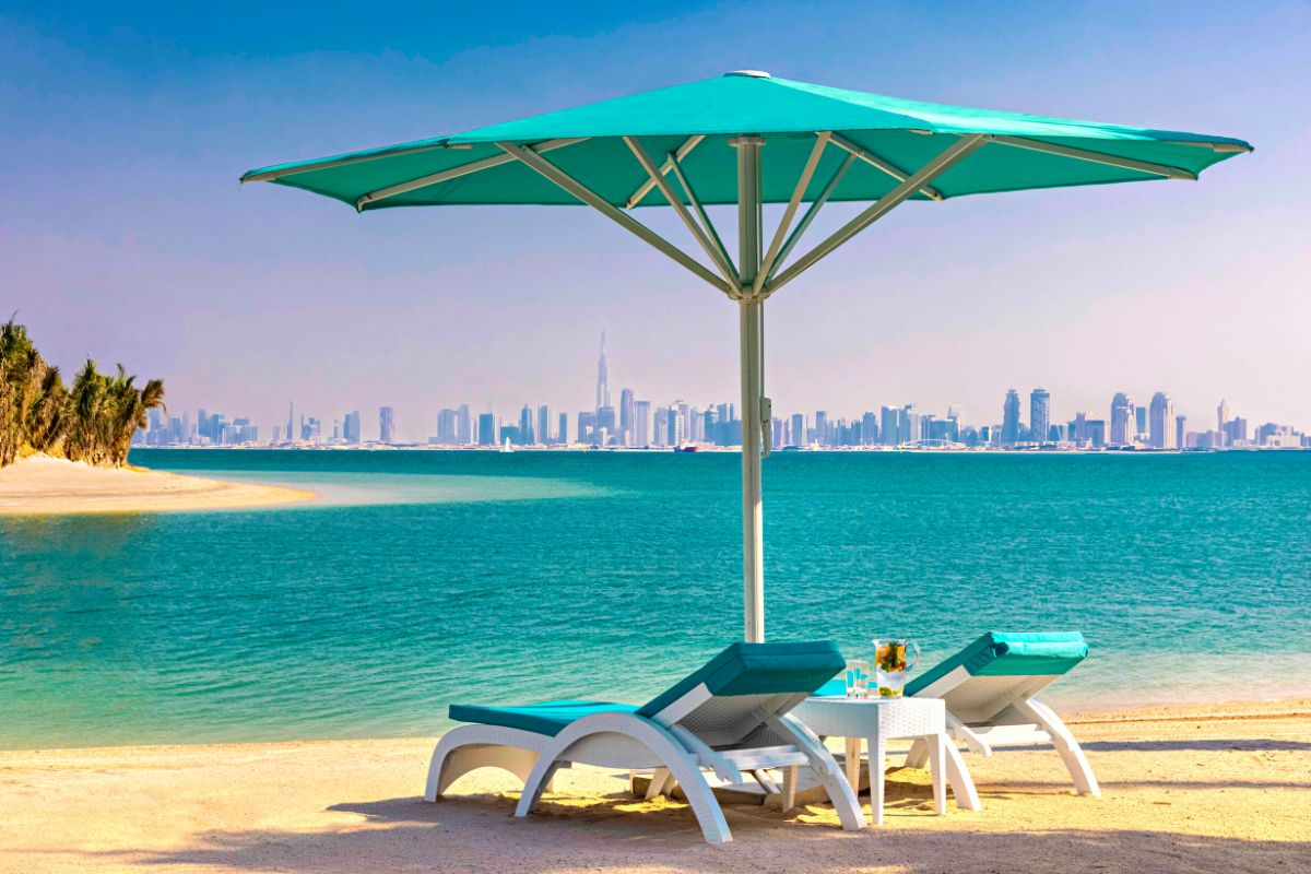Anantara World Islands Dubai Resort view with teal beach umbrella and sun chairs with a relaxing scenery