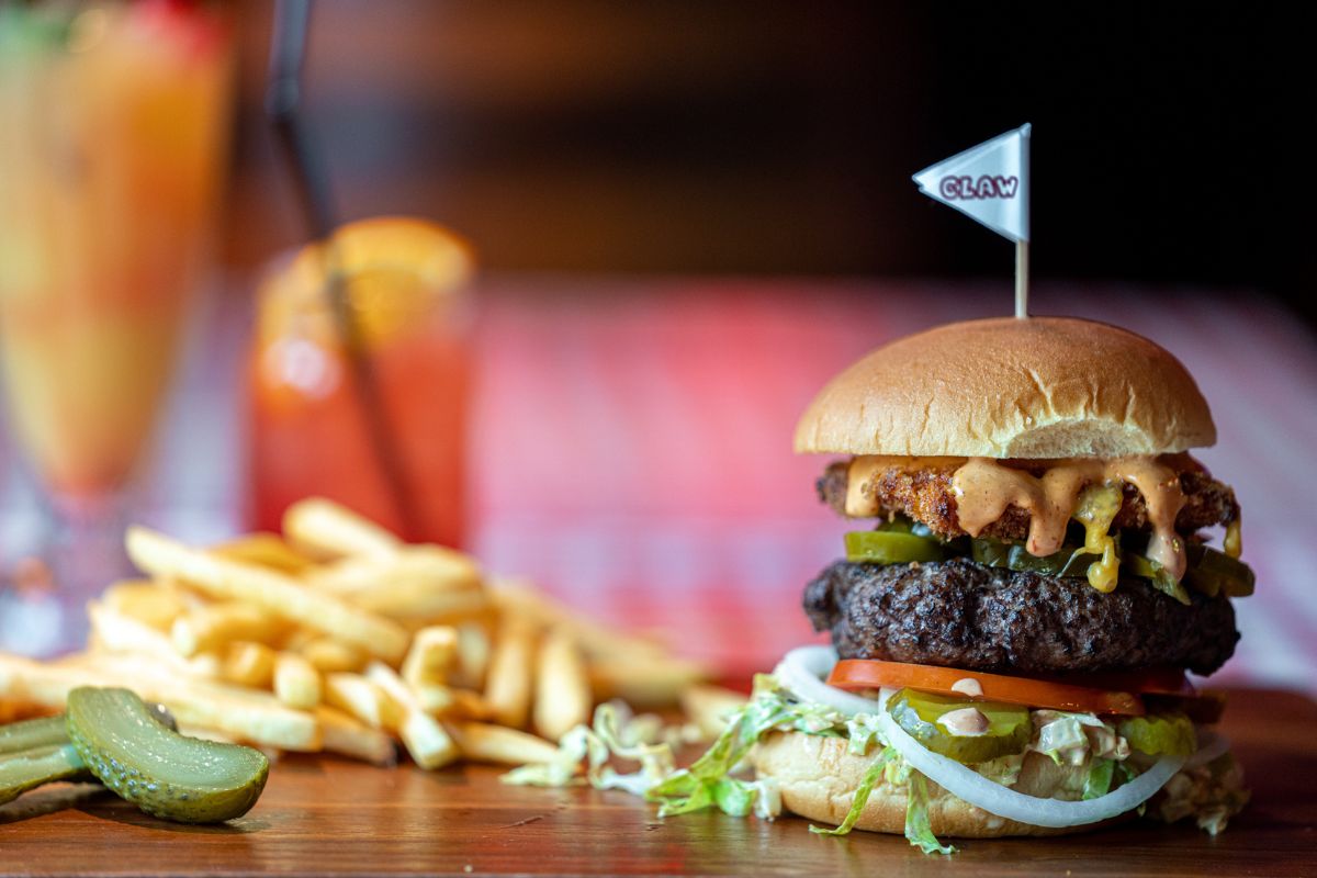 Claw BBQ Dubai signature burger with fries and pickles on the side
