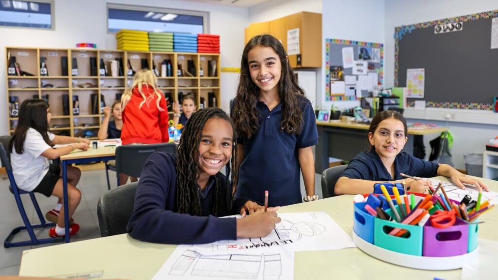 Bright classroom at American School of Dubai with smiling students and colourful supplies.