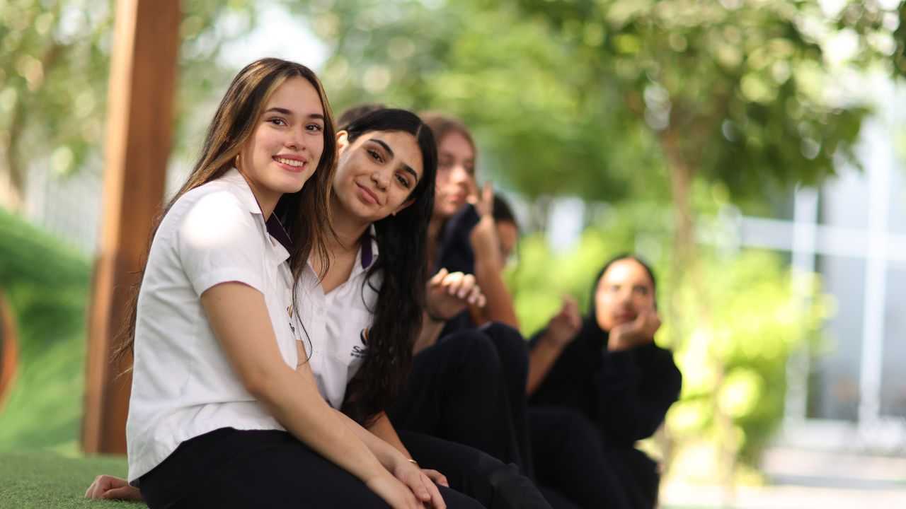 Group of happy students sitting outdoors at Safa British School, Dubai.