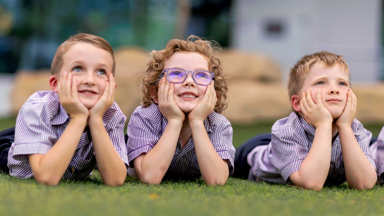 Happy children lying on grass at Safa Community School, Dubai.