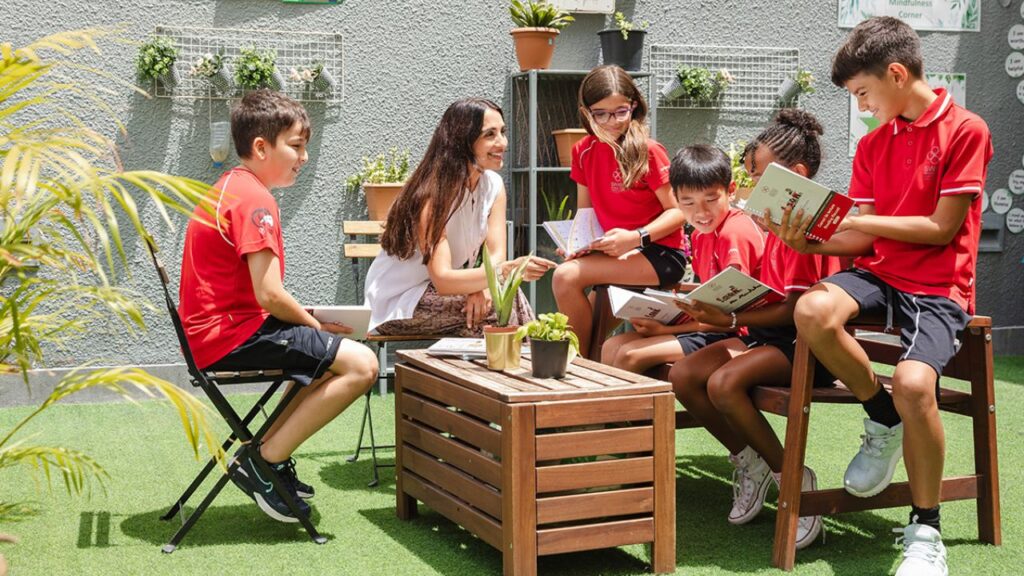 Children reading books outdoors at Yalla Dubai Life, promoting education and outdoor activities.