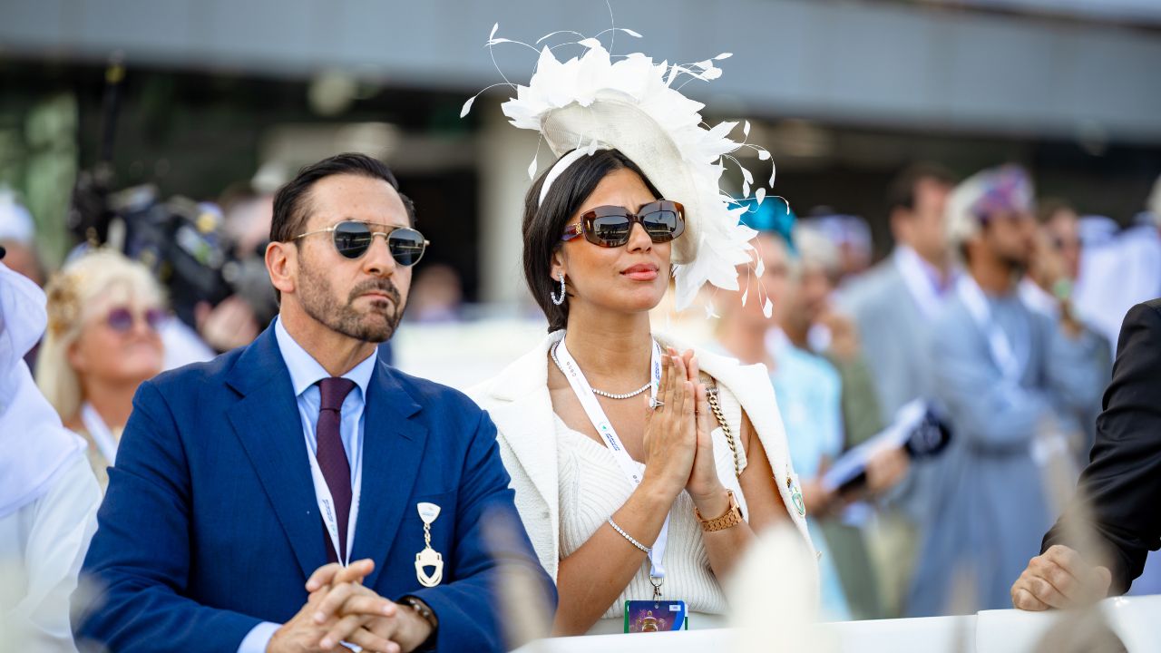 Elegant woman and man at Dubai racing event in stylish attire.
