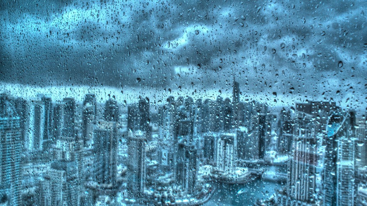 Rain-soaked Dubai skyline with heavy rainfall and city buildings under stormy skies.