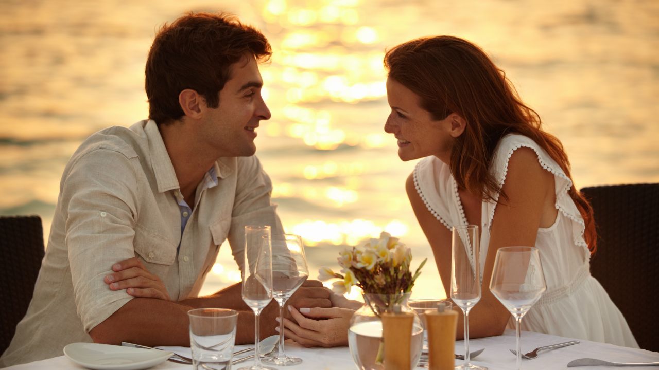 Romantic couple enjoying sunset dinner by the seaside at Aloha Beach.
