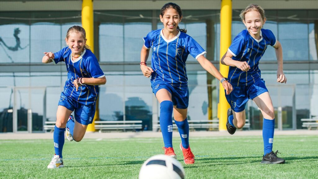 Youth girls playing soccer in Dubai sports field.