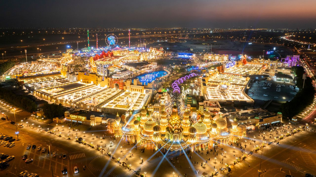 Vibrant night scene of Dubai's Global Village with illuminated rides and attractions.