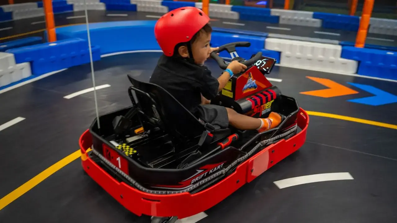 Child racing go-kart at indoor track in Dubai.