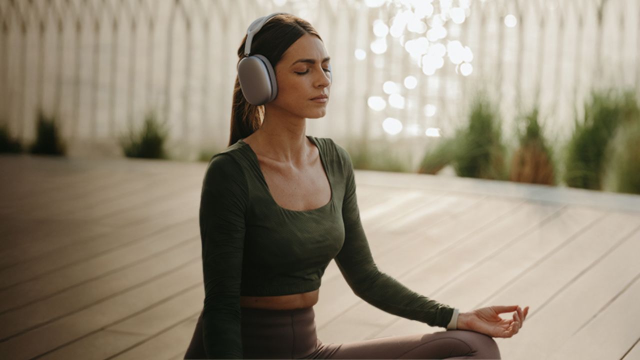 Woman meditating in a modern indoor space with headphones, promoting wellness and fitness.