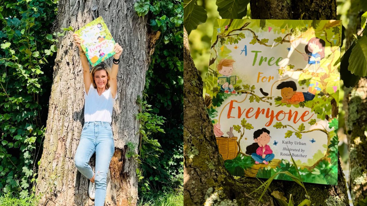 Young girl holding a signed book next to a tree.