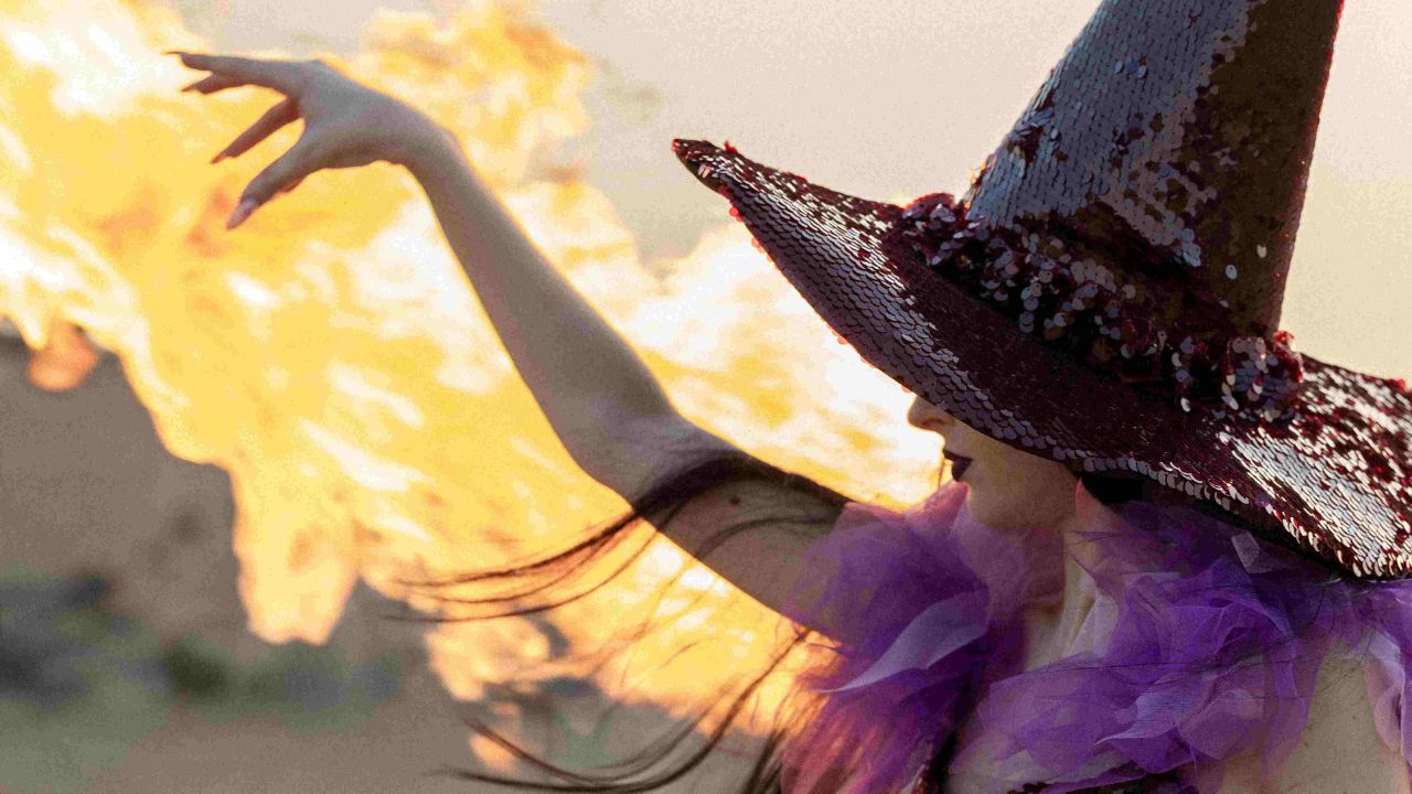Woman in witch costume with fire in desert for Halloween event Dubai.