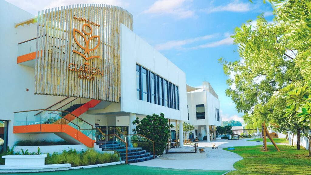 Modern Clarion School building with outdoor greenery and bright blue sky.