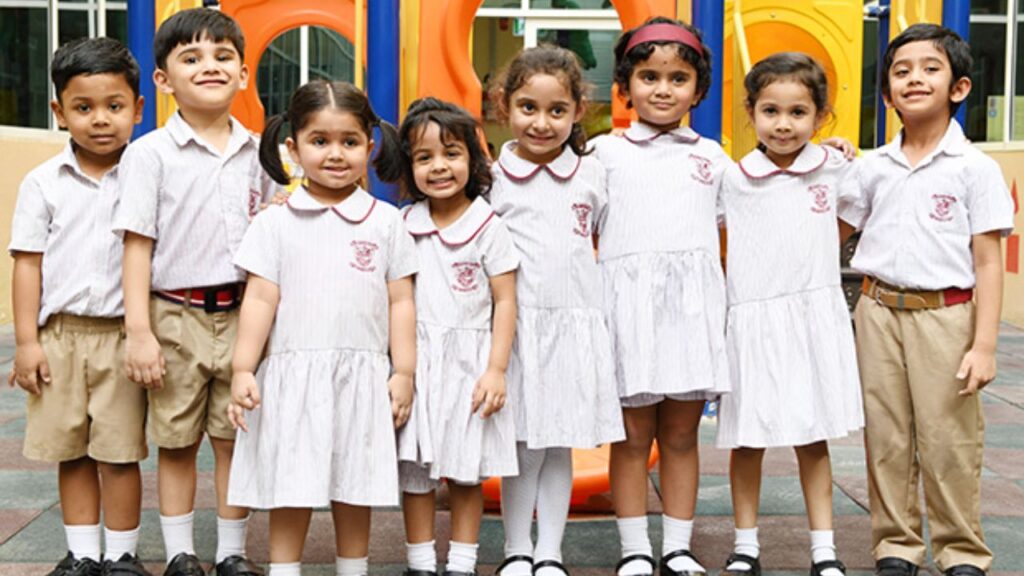Group of happy young students in school uniforms at GEMS Millennium School Sharjah playground.