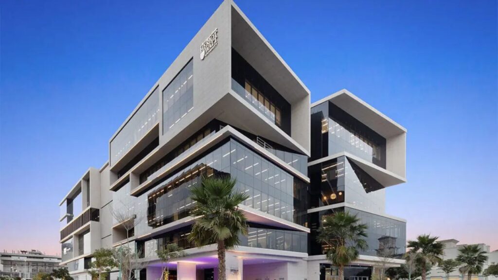 Modern Heriot-Watt University Dubai campus with glass facades and palm trees.