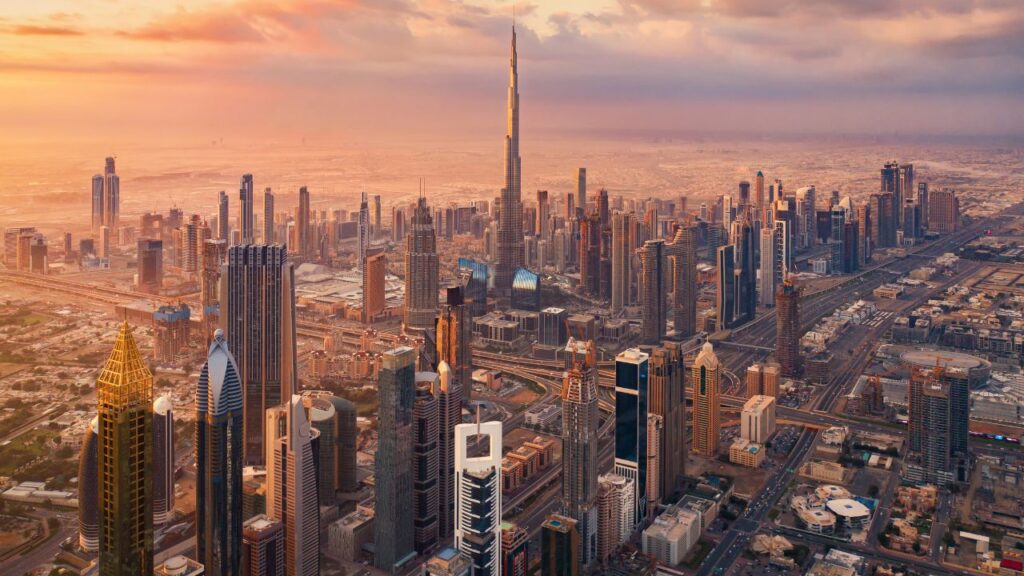 Aerial view of Dubai's cityscape featuring tall buildings and the Burj Khalifa at sunset.