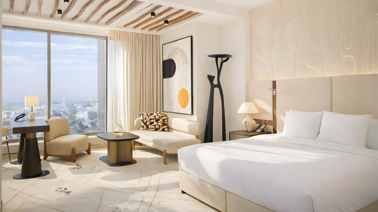 Modern hotel room at The H Dubai with a panoramic city view and elegant decor.